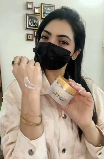 Dr, Hira Shakeel sapplying cream to her hand with a jar of cream in her other hand,