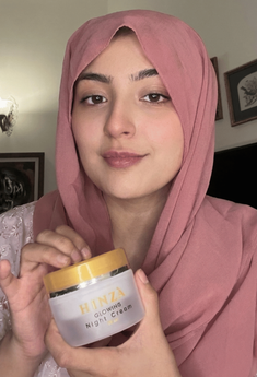 Woman holding a jar of 'Hinza' skincare product in a home setting